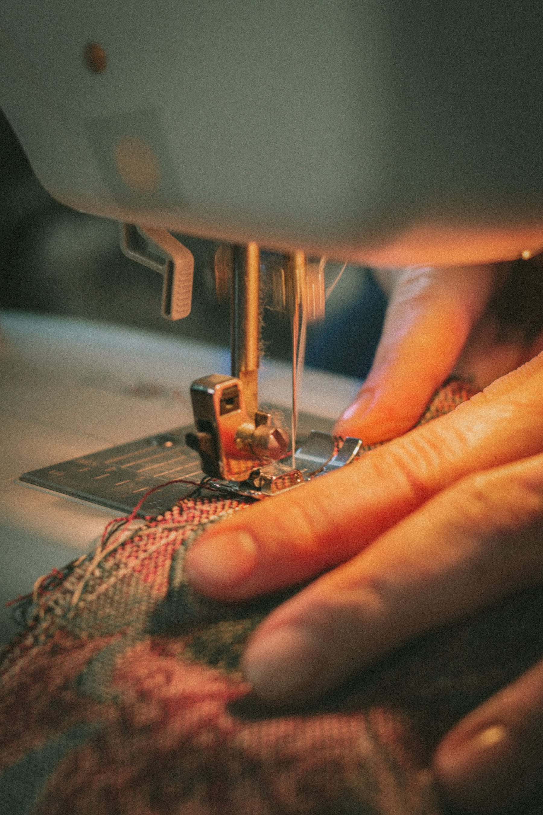 Hände führen Stoff durch eine Industrienähmaschine